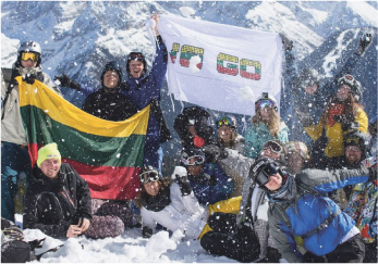 Būrys alpinistų pozuojantys fotografui, laiko Lietuvos vėliavą ir WE GO vėliavą.