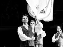 KTU tautinio meno ansamblis „Nemunas“ pasirodymo metu, vaikinas apsirengęs tautinį kostiumą, neša kolektyvo vėliavą