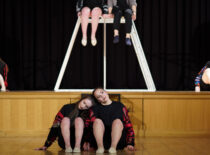 KTU šokių studija „Modance“ pasirodymo metu, dvi merginos sėdi apačioje (žemiau scenos) ir vaikinas su mergina viršuje scenos