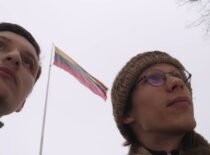 Du žmonės stovi vėliavos fone