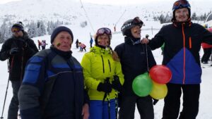 Doc. dr. E. Karčiauskas pozuoja kalnuose kur slidinėjo. Žmonėms ant veidų nupieštos Lietuvos vėliavos.