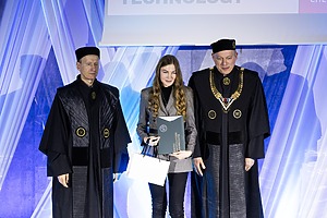 Doktorantė atsiėmusi diplomą stovi šalia Rektoriaus ir prorektoriaus.